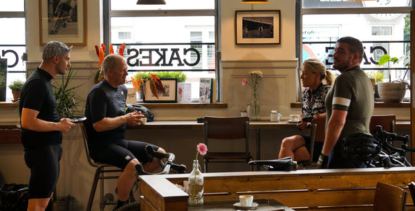 Cyclist sit and chat whilst drinking Bad Hand Coffee in the Rockets and Rascals Cycling Cafe, Poole, Dorset.