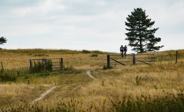 Two cyclists partaking in the Rockets and Rascals monthly gravel social ride crest a hill in the Isle of Purbeck as part of their 