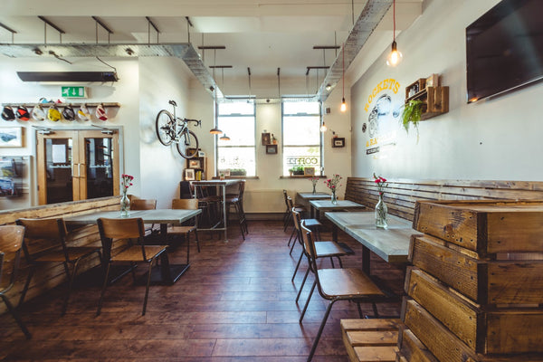 The interior seating area of the Rockets and Rascals bicycle cafe in Poole, Dorset. The walls are filled with bikes, memorabilia, books and a television showing live bicycle racing. The cafe also has a variety of seating available.